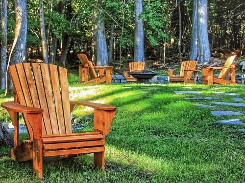 a group of wooden chairs sitting in the grass at Destination Franc Sud Gaspésie in Cascapedia