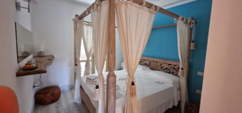 a bedroom with a four poster bed with curtains at LOTUS Wellness Apartment - Resort Ginestre - Palau - Sardinia in Palau