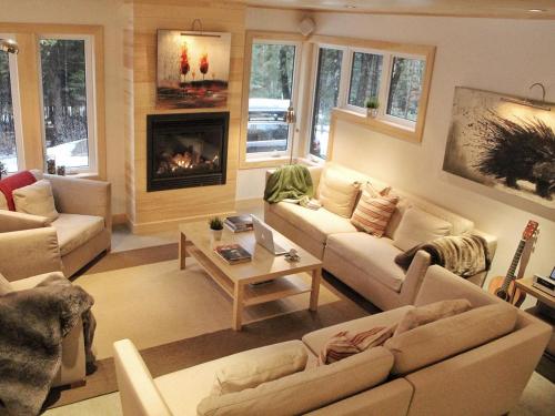 a living room with couches and a fireplace at Destination Franc Sud Gaspésie in Cascapedia