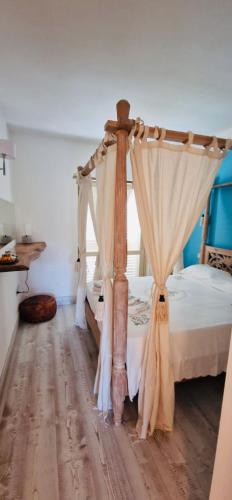 a bedroom with a canopy bed with curtains at LOTUS Wellness Apartment - Resort Ginestre - Palau - Sardinia in Palau