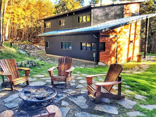 three chairs and a fire pit in front of a house at Destination Franc Sud Gaspésie in Cascapedia