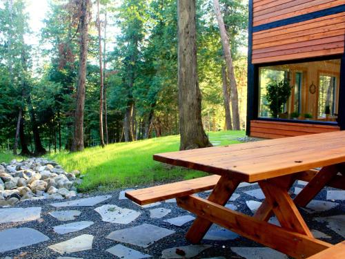 a wooden picnic table sitting outside of a cabin at Destination Franc Sud Gaspésie in Cascapedia
