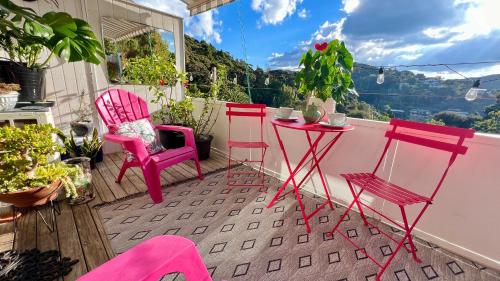 un grupo de sillas rosas y una mesa en el balcón en Paihia Loft Walk to Beach, Eats and Culture, en Paihia