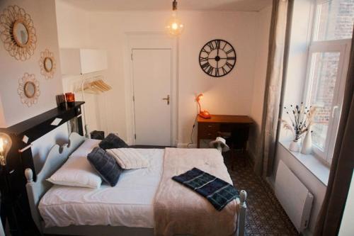 a bedroom with a bed and a clock on the wall at Au Béguinage - Studio au coeur de wavre in Wavre