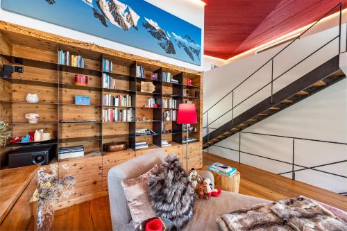 a living room with a book shelf and a staircase at Maison Montagne in Samedan