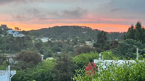 - une vue sur une colline avec des arbres et un coucher de soleil dans l'établissement Paihia Loft Walk to Beach, Eats and Culture, à Paihia