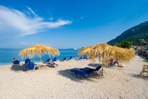 a group of chairs and straw umbrellas on a beach at Potamaki Beach Hotel in Benitses