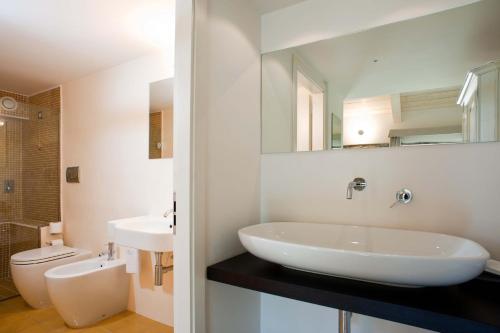 a white bathroom with a sink and a toilet at Rupe Alta Home in Castellabate