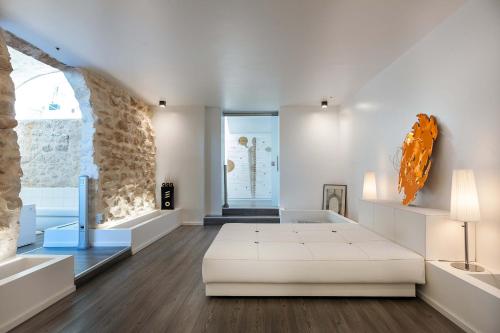 Habitación con cama blanca y pared de piedra. en Villa Luna, en Scicli