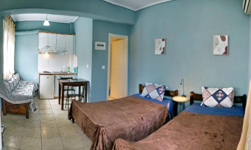 Habitación azul con 2 camas y cocina en Studios Akrotiri, en Mytilini
