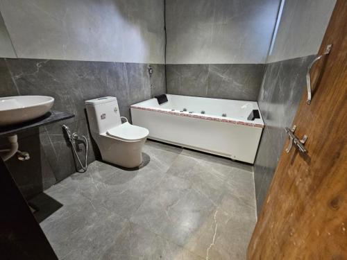 a bathroom with a tub and a toilet and a sink at Nova Park in Rajkot