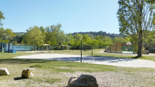 um parque com um parque infantil e um baloiço em Mobil Home vue sur le lac dans un camping 4 étoiles à Cadenet em Cadenet