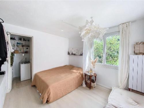 une chambre blanche avec un lit et une fenêtre dans l'établissement Un nid paisible à 12min de Paris, à Colombes