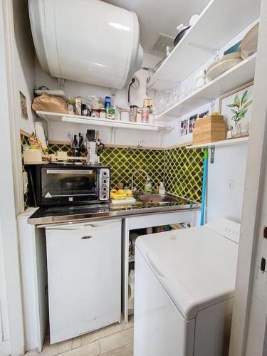 une petite cuisine avec une cuisinière et un micro-ondes dans l'établissement Un nid paisible à 12min de Paris, à Colombes