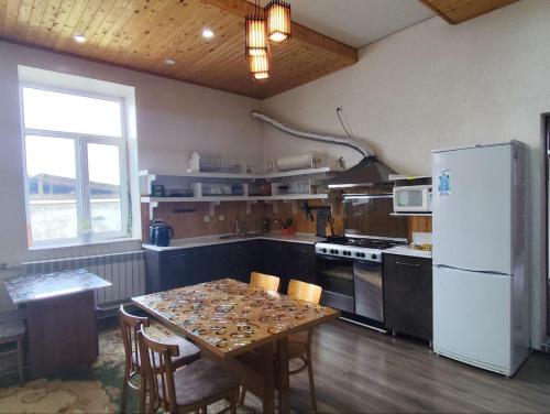 a kitchen with a table with chairs and a refrigerator at Urban Monkey Tent hostel & bar in Karakol