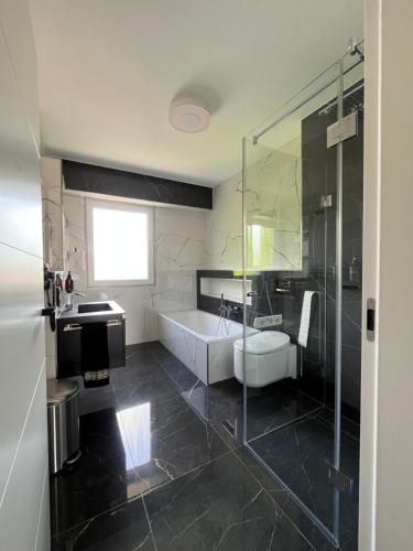 ブクステフーデにあるExklusives Penthouse in Buxtehude !!の浴槽、洗面台、シャワーを備えたバスルーム