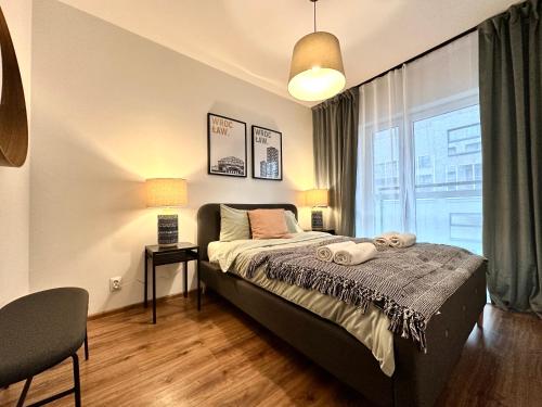 een slaapkamer met een bed en een groot raam bij Momo Apartamenty in Wrocław