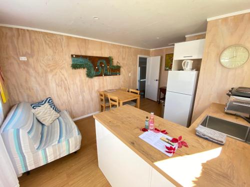 uma cozinha e sala de estar com um sofá e uma mesa em Beachside Gem - Cosy Chalet em Parapara 