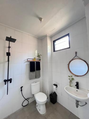 a white bathroom with a toilet and a sink at Nomad Cottage in Amed