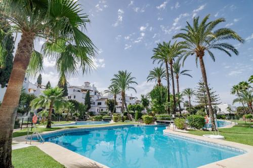 una piscina con palmeras y edificios en AB2 - Aldea Blanca Marbella by Roomservices en Marbella
