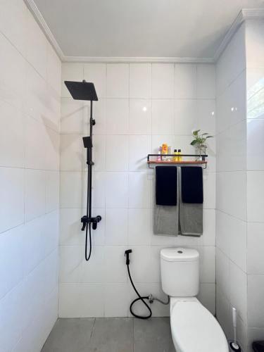 a white bathroom with a toilet and a shower at Nomad Cottage in Amed