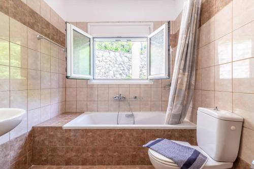 bagno con vasca, servizi igienici e finestra di Lovely Maisonette in the village a Márathos