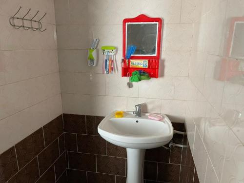 a bathroom with a white sink and a mirror at Nice Mini Hotel in Sary-Mogul