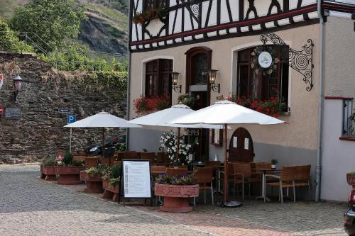 um restaurante com mesas e guarda-sóis em frente a um edifício em Hotel Weiler em Oberwesel