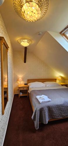 um quarto com uma cama grande e um lustre em Zamecky Hotel Lednice em Lednice