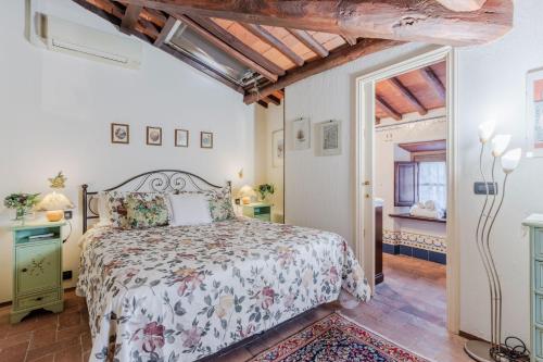 a bedroom with a bed with a floral bedspread at Le Bicocche Farmhouse: Country Stone Villa with Pool in Camaiore between Lucca & Beaches of Versilia in Montemagno