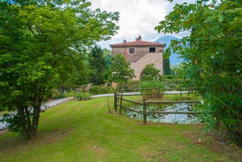 a building in a park with a pond and trees at Le Bicocche Farmhouse: Country Stone Villa with Pool in Camaiore between Lucca & Beaches of Versilia in Montemagno