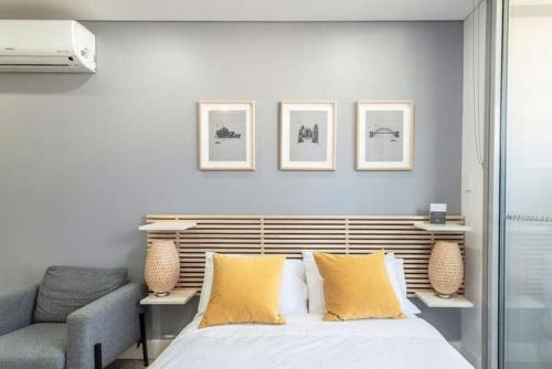 um quarto com uma cama com almofadas amarelas e uma cadeira em Studio in Crown St - Private Balcony & Aircon em Sydney