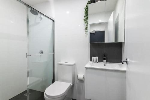 a white bathroom with a toilet and a sink at Studio in Crown St - Private Balcony & Aircon in Sydney