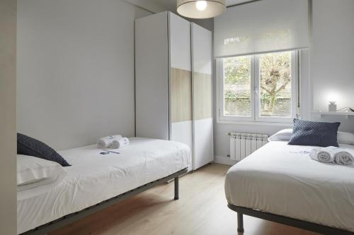 1 dormitorio con 2 camas y ventana en Ategorri - Basque Stay, en San Sebastián