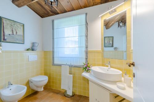 een badkamer met 2 wastafels, een toilet en een spiegel bij La Vaseria Country House with Secret Garden and pool in Ghivizzano