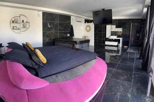 - une chambre avec un grand lit rose et un bureau dans l'établissement Chambres des délices, à Villetelle
