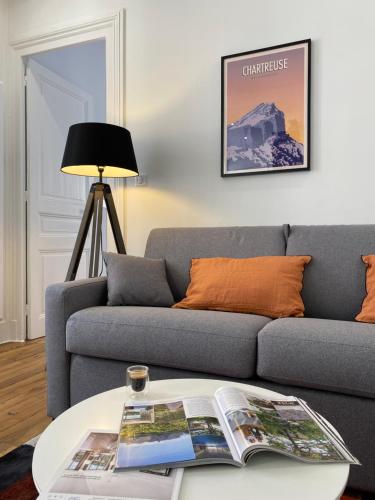 - un salon avec un canapé et un journal sur une table dans l'établissement La Suite Championnet, à Grenoble
