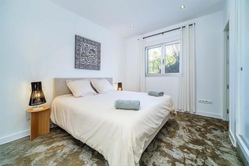 a white bedroom with a large bed and a window at Casa de la Luz 4 pax in Montgo