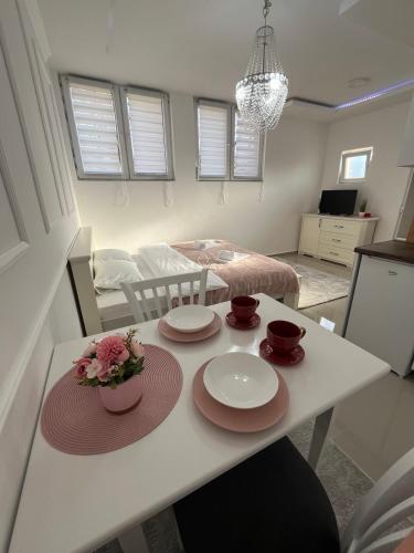 a kitchen and living room with a table with plates on it at Zlatni bor apartmani in Solotuša