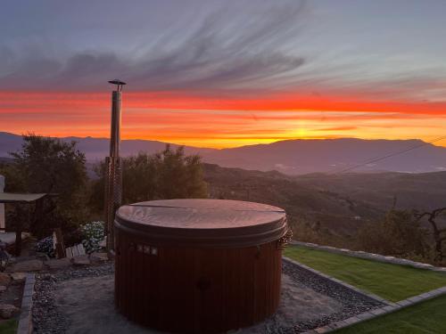 a large barrel sitting on top of a hill with a sunset at Cortijo Los Maximos in Turón
