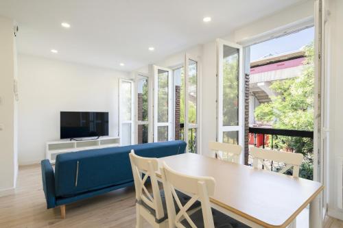a living room with a blue couch and a table and chairs at apartamentos en la avda de la albufera ALQUILER TEMPORAL in Madrid