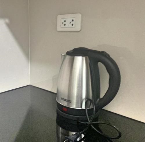 a tea kettle on a counter with a clock on the wall at Cozy studio unit in Boracay Newcoast in Boracay