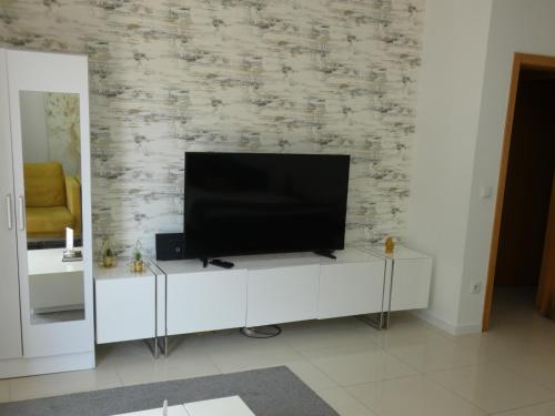 a television on a white cabinet in a living room at Villa Barrinha in Praia de Mira