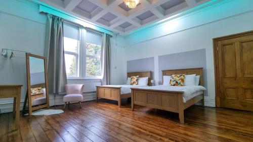 a bedroom with two beds and a window at Sleeps 20 Stunning Ashton Mansion in Ashton under Lyne