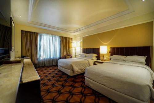 a hotel room with two beds and a television at Sheraton Grand Pune Bund Garden Hotel in Pune