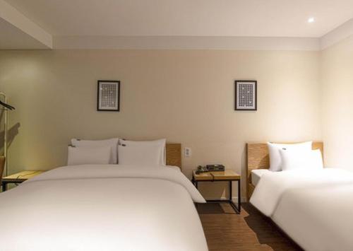 2 bedden in een hotelkamer met witte lakens bij 3S Hotel Sorae in Incheon