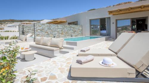 un patio con muebles blancos y una piscina en Solus Suites Milos en Adamas
