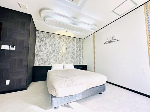 a bedroom with a bed and a wall at One Style in Naha