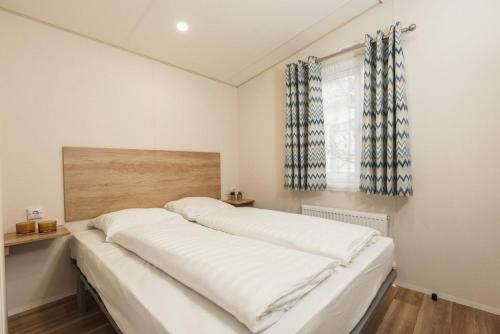 1 dormitorio con 1 cama grande con sábanas blancas en Mobile home 6 persons I Basic, en Zuna