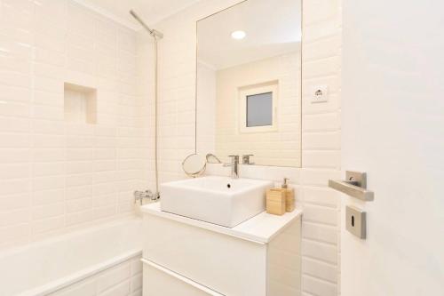 La salle de bains blanche est pourvue d'un lavabo et d'une baignoire. dans l'établissement MY LX FLAT Stylish Apartment in Santa Catarina, à Lisbonne